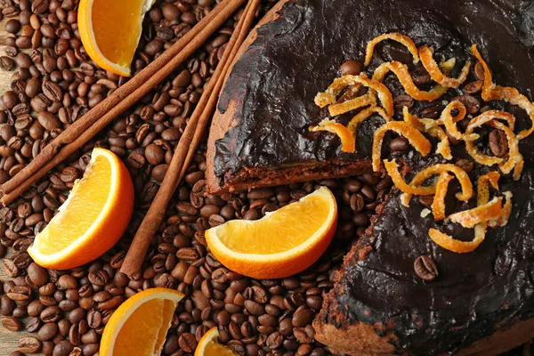 Gâteau avec glaçage au chocolat et orange sur assiette, sur fond de grains de café — Photo