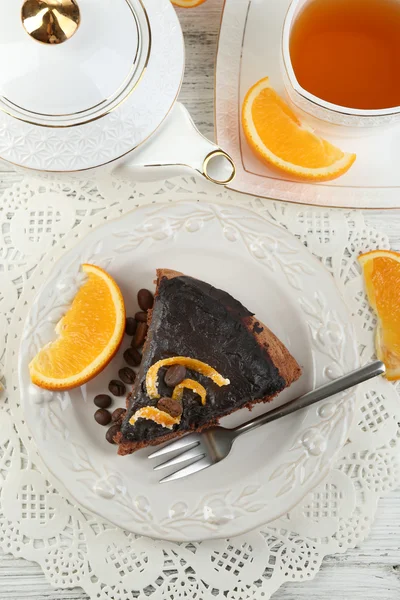 Κέικ με γλάσο σοκολάτας και πορτοκάλι στο πιάτο, σε ξύλινο φόντο — Φωτογραφία Αρχείου