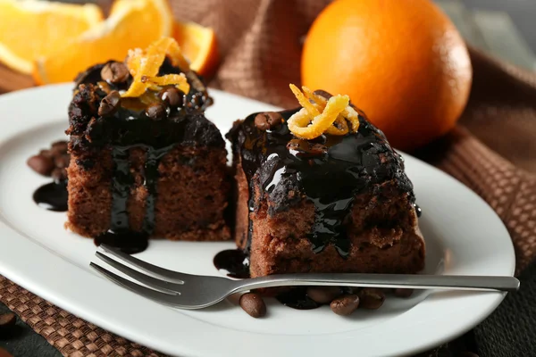 Porzione di torta con glassa al cioccolato e arancia su piatto, su fondo di legno — Foto Stock