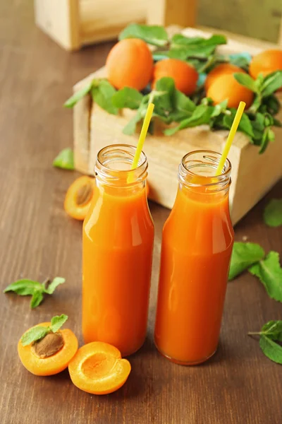 Bouteilles de jus d'abricot et fruits frais sur la table close up — Photo