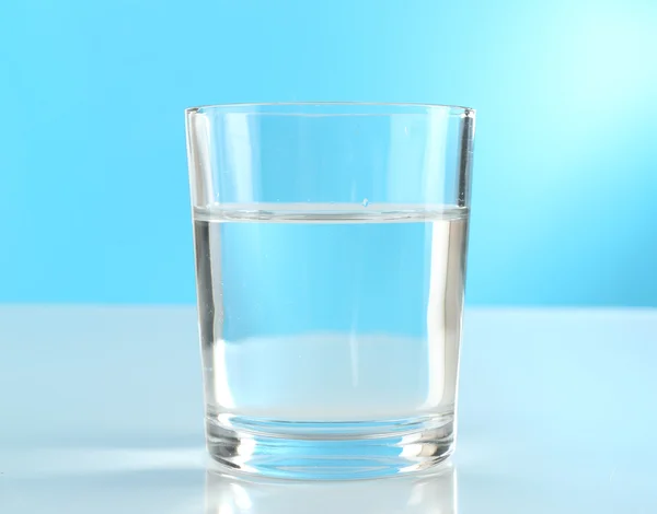 Glass of water on blue background — Stock Photo, Image