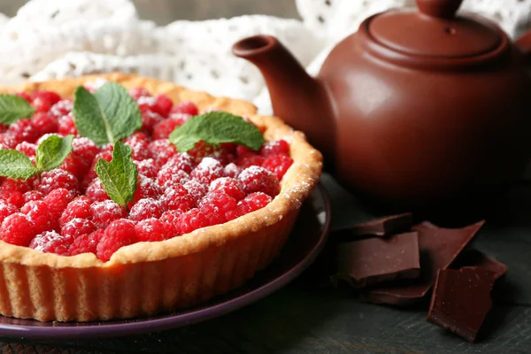 Tart with fresh raspberries and teapot, on wooden background — Stock Photo, Image