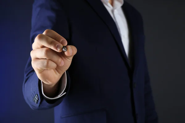 Businessman in suit with pen on dark background — Stock Photo, Image