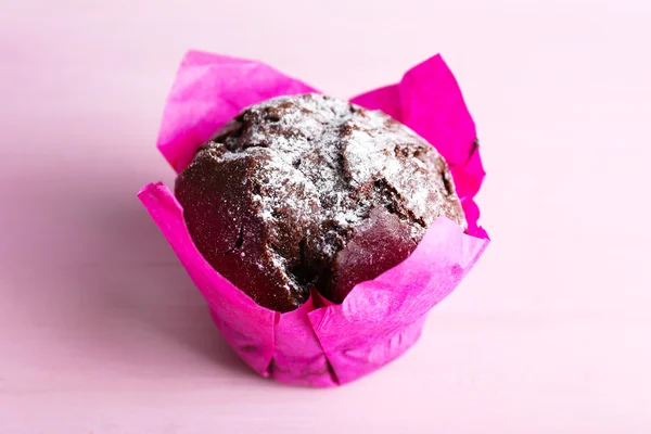 Choklad cupcake i rosa papper på träbord, närbild — Stockfoto