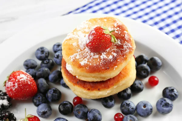 Fritters of cottage cheese with berries in plate on table, closeup — Stock Photo, Image