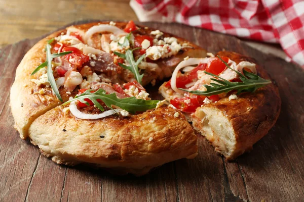 Pizza casera griega con jamón, cebolla, tomate asado, queso feta cremoso sobre tabla de madera, sobre fondo de mesa — Foto de Stock