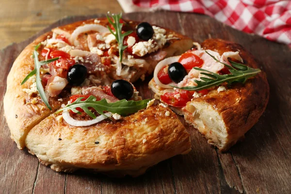 Pizza casera griega con jamón, cebolla, tomate asado, queso feta cremoso sobre tabla de madera, sobre fondo de mesa — Foto de Stock