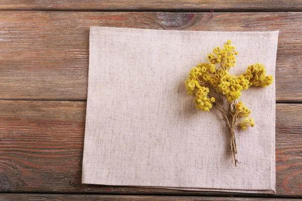 Beautiful dry flowers on napkin on wooden background — Stock Photo, Image