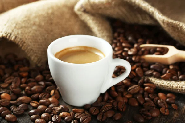 Cup of coffee with beans on table close up — Stock Photo, Image