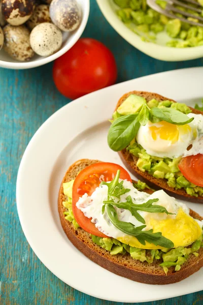 Läckra mackor med ägg, avokado och grönsaker på tallriken, på trä bakgrund — Stockfoto