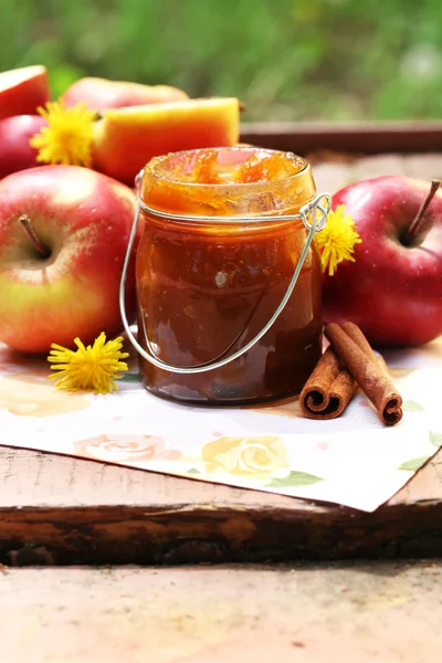 Apple jam in jar and fresh red apples outdoors — Stock Photo, Image