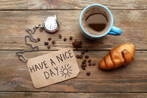 Taza de café con croissant fresco y tener un buen día de masaje en la mesa de madera, vista superior — Foto de Stock