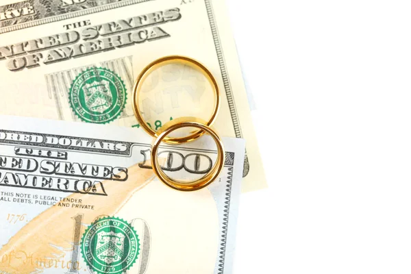 Anelli nuziali dorati su banconote, isolati su bianco. Matrimonio di convenienza — Foto Stock