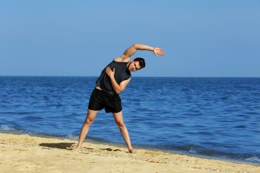 Genç adam sportif plajda egzersiz yaparak