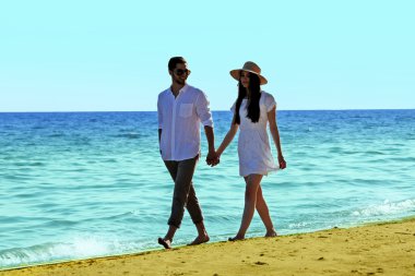 Genç bir çift sahilde yürüyor.