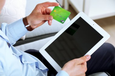 Kredi kartı ve tablet tutan adam