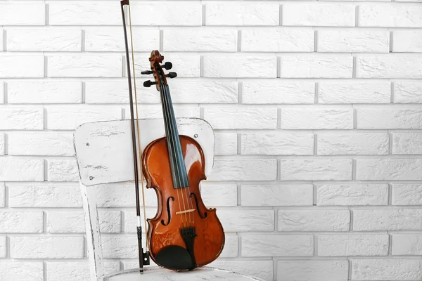 Violino na cadeira, no fundo da parede de tijolos — Fotografia de Stock