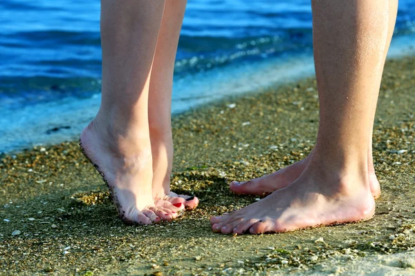 Mannelijke en vrouwelijke benen op zand van het strand — Stockfoto