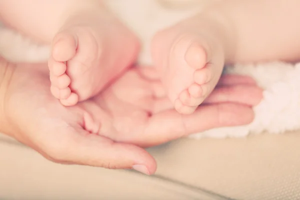 Mãos adultas segurando os pés do bebê, close-up — Fotografia de Stock