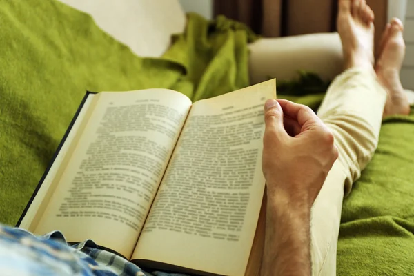 Young man reading book on sofa close up — Stock Photo, Image