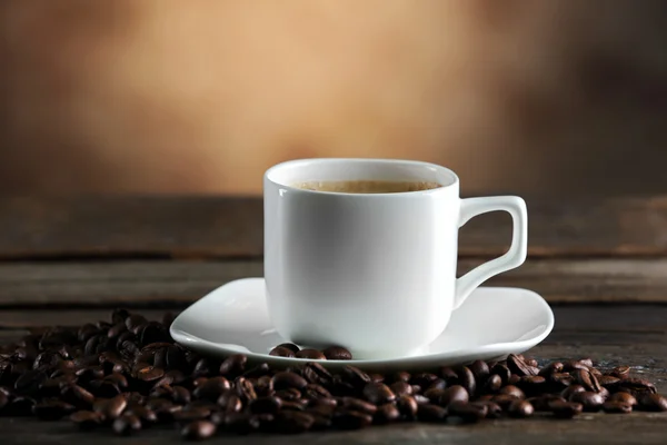 Tasse Kaffee und Bohnen auf verschwommenem Hintergrund — Stockfoto