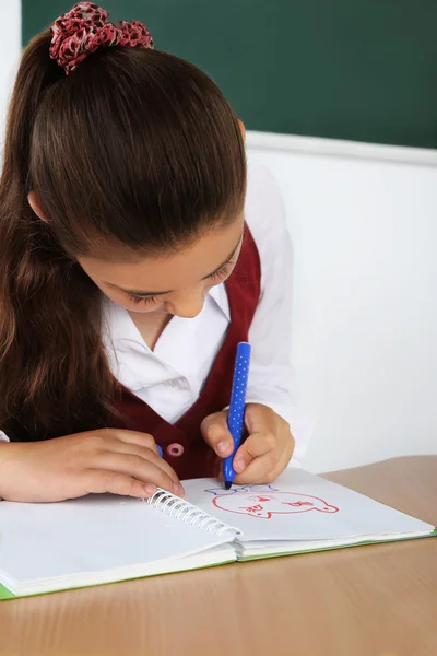 Piękne małe uczennica w klasie i rysuje w notesie — Zdjęcie stockowe