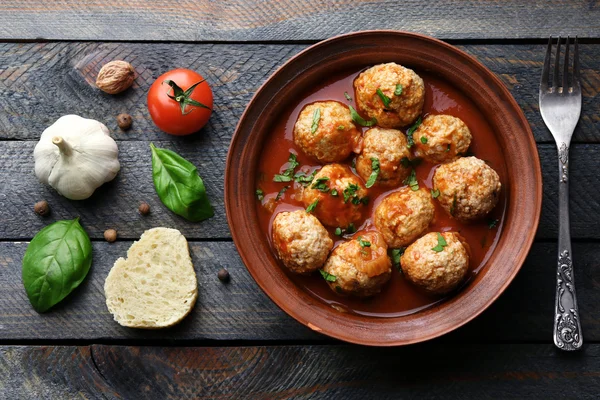 Meat balls with tomato sauce and ingredients on wooden background — Stock Photo, Image