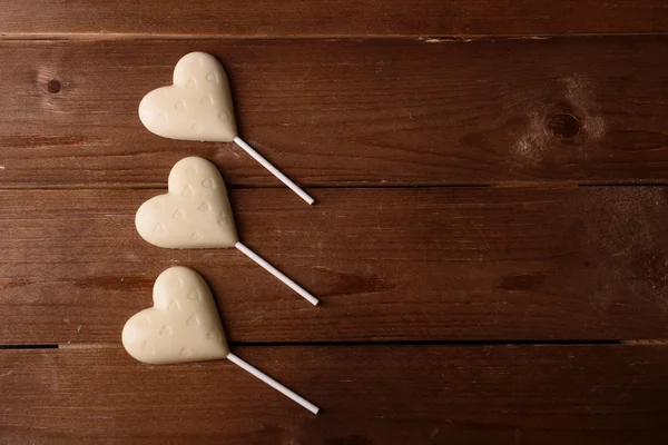 Doces de chocolate em forma de corações em fundo de madeira — Fotografia de Stock