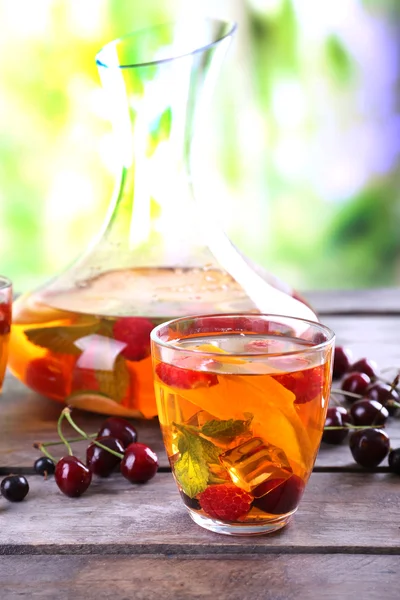 Punch with berries in glassware on wooden table on light blurred background — Stock Photo, Image