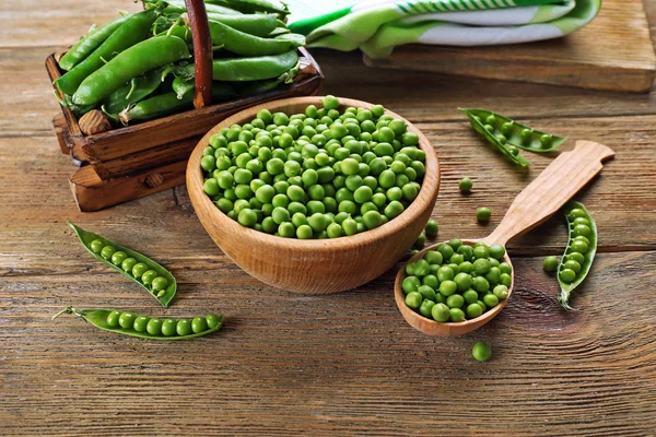 Ervilhas verdes frescas na tigela e colher na mesa de perto — Fotografia de Stock