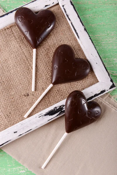 Choklad hjärtformade godis på pinnar på säckväv, närbild — Stockfoto