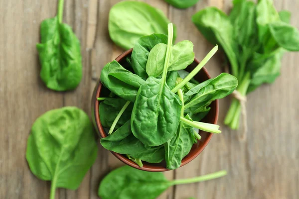 Bowl of fresh spinach leaves on wooden table, closeup — Stock Photo, Image