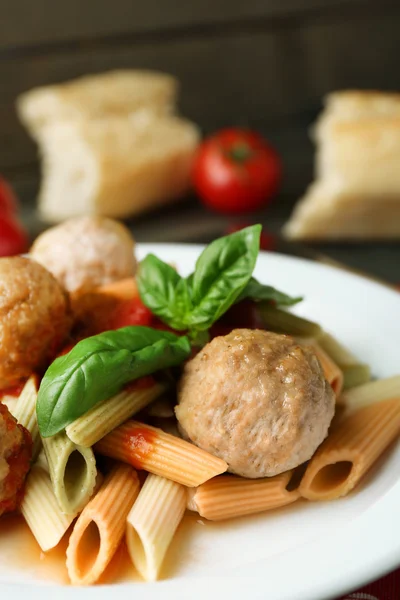 Pasta con albóndigas en plato, sobre fondo de mesa de madera —  Fotos de Stock