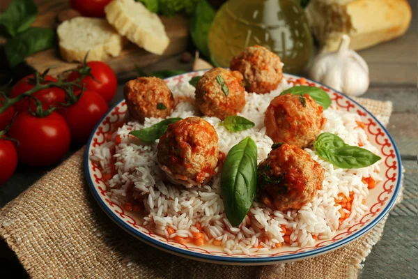 Meat balls in tomato sauce with boiled rice and lentil, wooden spoon on wooden background — Stock Photo, Image