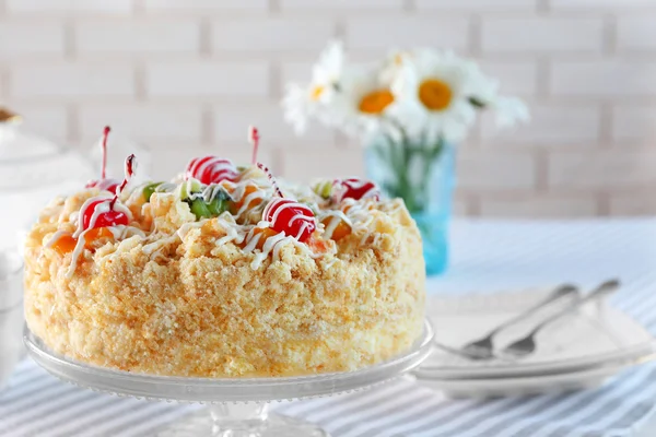 Smör tårta med körsbär på stativ och dukningen på ljus bakgrund — Stockfoto