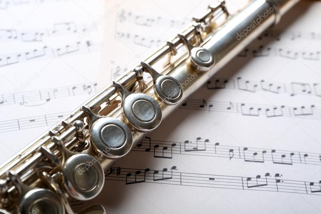Silver flute on music notes background Stock Photo by ©belchonock 79063842