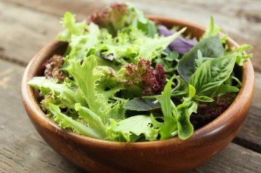 Ahşap masa üzerinde kase taze karışık yeşil salata yakın çekim