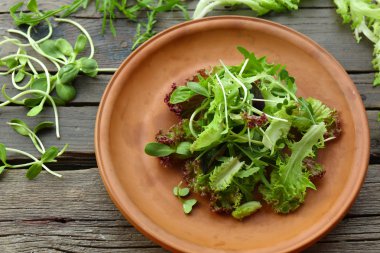 Ahşap masa üzerinde taze karışık yeşil salata tabak kapat
