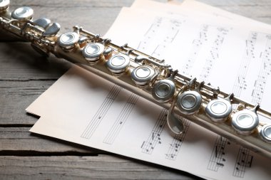 Ahşap masa üzerine müzik notlar ile gümüş flüt yakın çekim