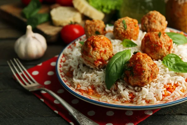 Bolas de carne en salsa de tomate con arroz hervido y lentejas, cuchara de madera sobre fondo de madera —  Fotos de Stock