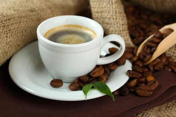 Cup of coffee with beans on table close up — Stock Photo, Image