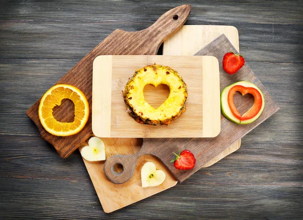 Fruits slices with cut in shape of heart and berries on table close up — Stock Photo, Image