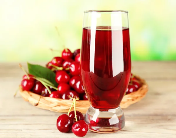 Glass of fresh juice with cherries on bright background — Stock Photo, Image