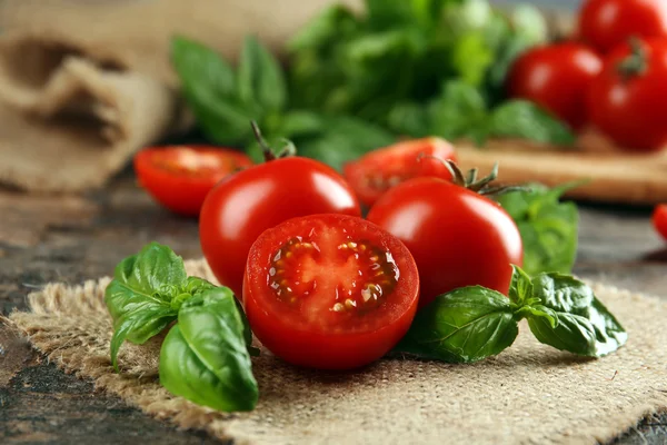 Cherry tomatoes with basil on wooden table close up