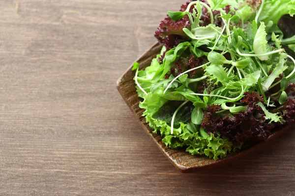 Ahşap masa üzerinde taze karışık yeşil salata tabak kapat — Stok fotoğraf