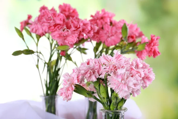 Beautiful bouquet of pink carnation in vases on bright background — Stock Photo, Image
