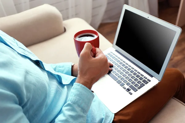 Man working with laptop on sofa in room — Stock Photo, Image