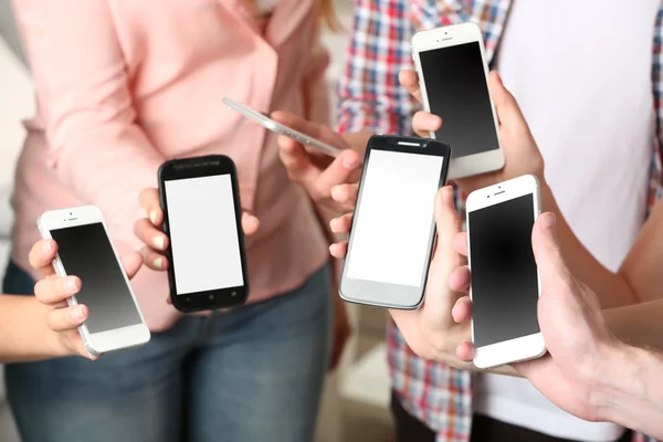 Muitas mãos segurando telefones celulares de perto — Fotografia de Stock