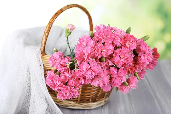 Krásná kytice růžový karafiát v koši na světlé pozadí — Stock fotografie