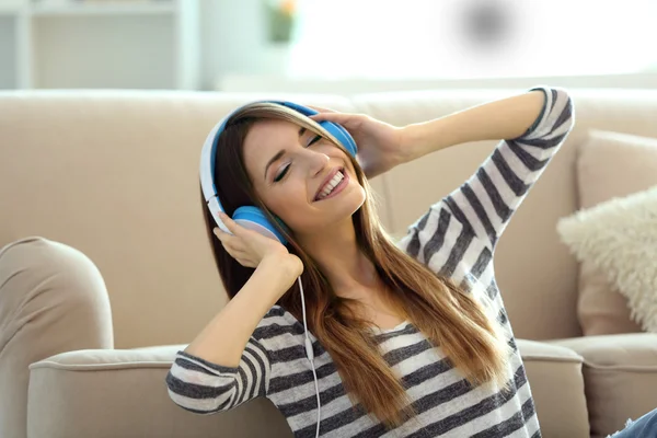 Vrouw die muziek luistert in hoofdtelefoon in de kamer — Stockfoto